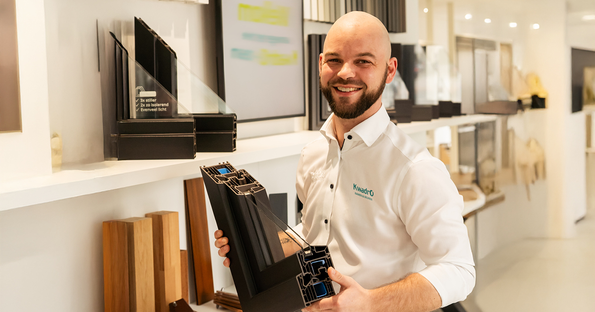 Adviseur van KwadrO in een toonzaal met een raamprofiel in zijn handen