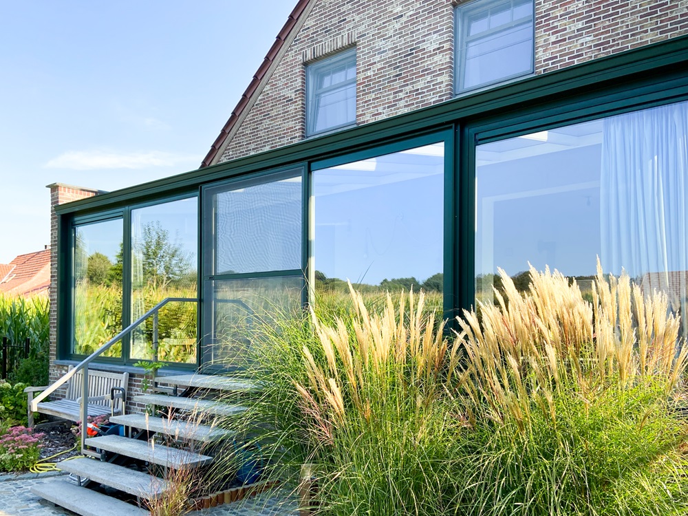 Groene pvc schuiframen met daarvoor siergrassen