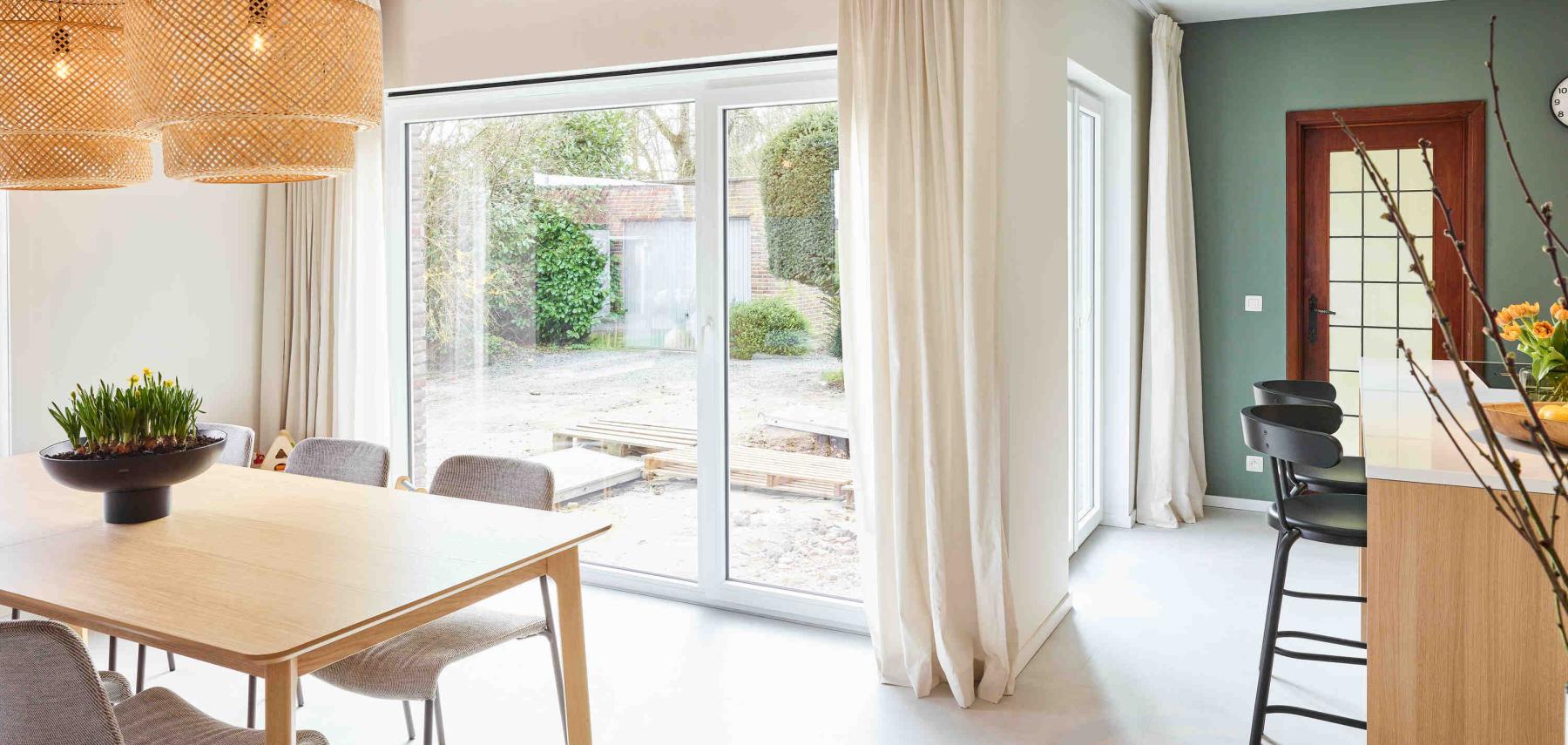 Lichtrijke eetruimte door het grote pvc raam dat de ruimte verbindt met de tuin