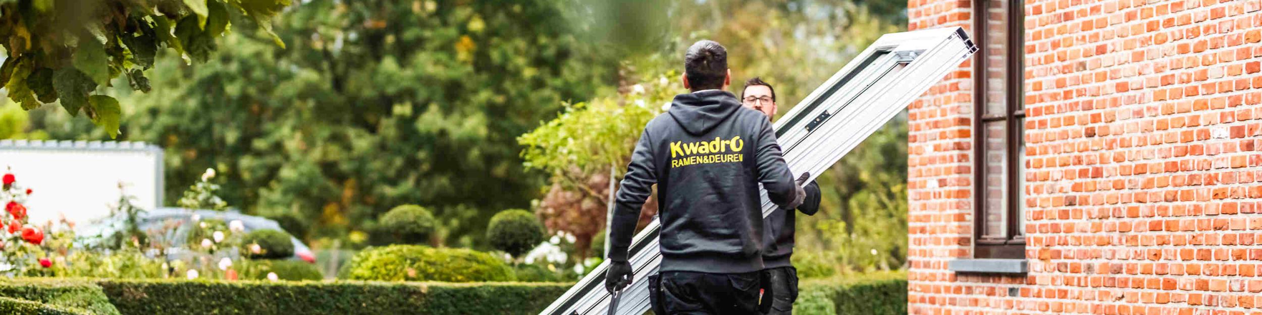 Twee plaatsers van KwadrO die een groot raam gaan plaatsen
