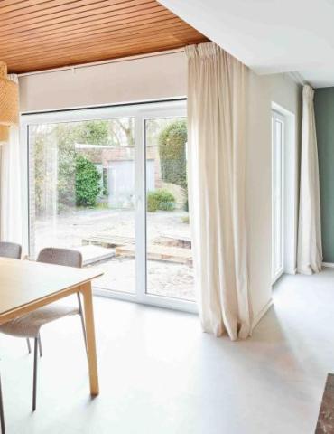 Lichtrijke eetruimte door het grote pvc raam dat de ruimte verbindt met de tuin