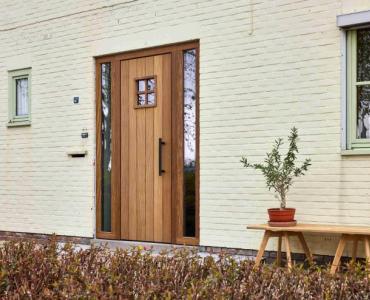Houten deur in afrormosia met een raam met kruisverdeling en vericale plankenstructuur in het deurpaneel